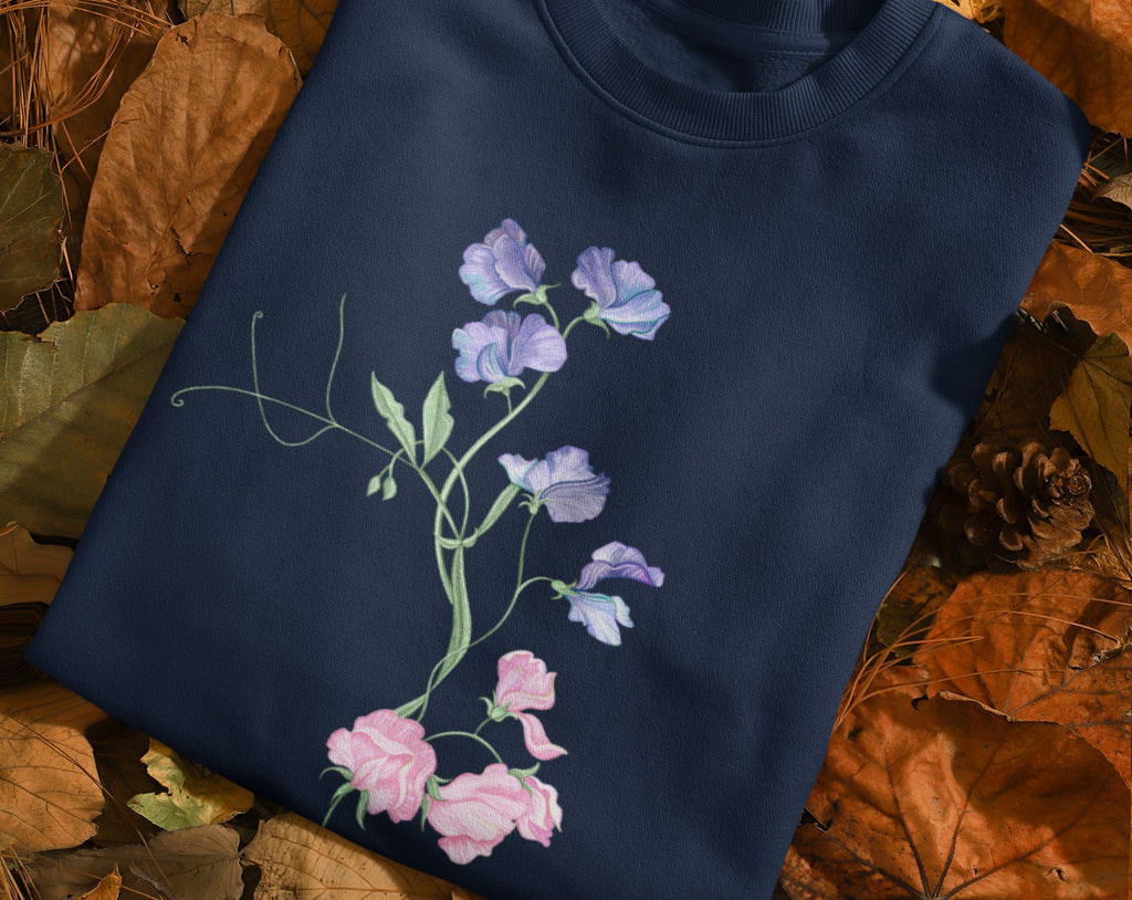 flat lay of a folded, navy sweet pea jumper on autumn leaves