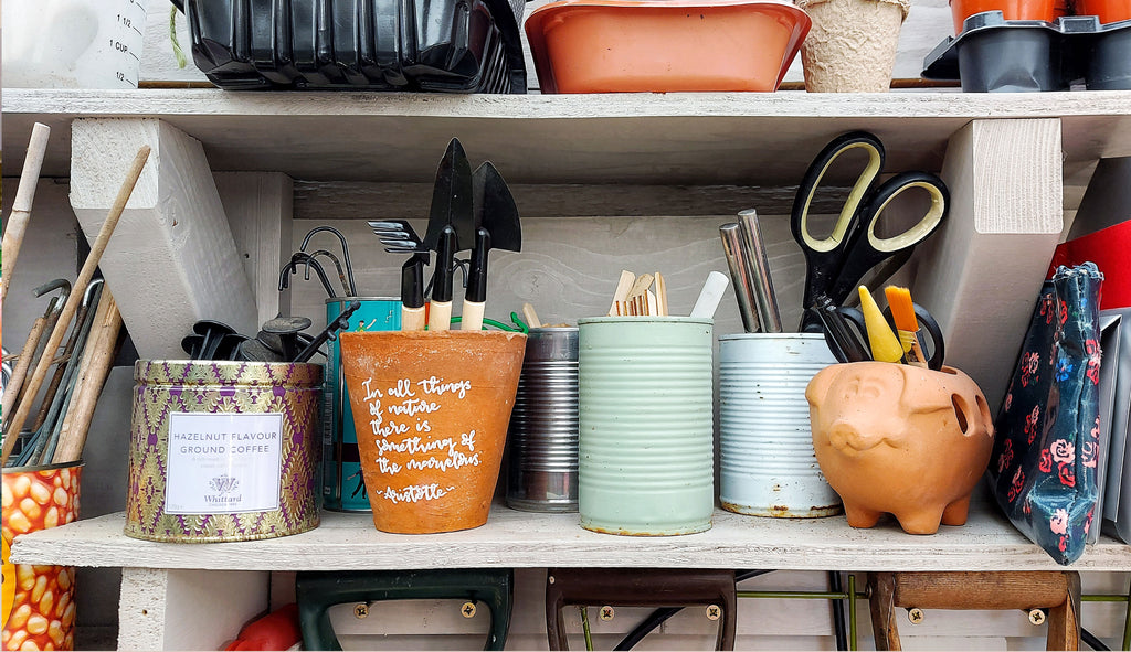 tins, pots and garden sundries on a shelf inside a grey, wooden shed