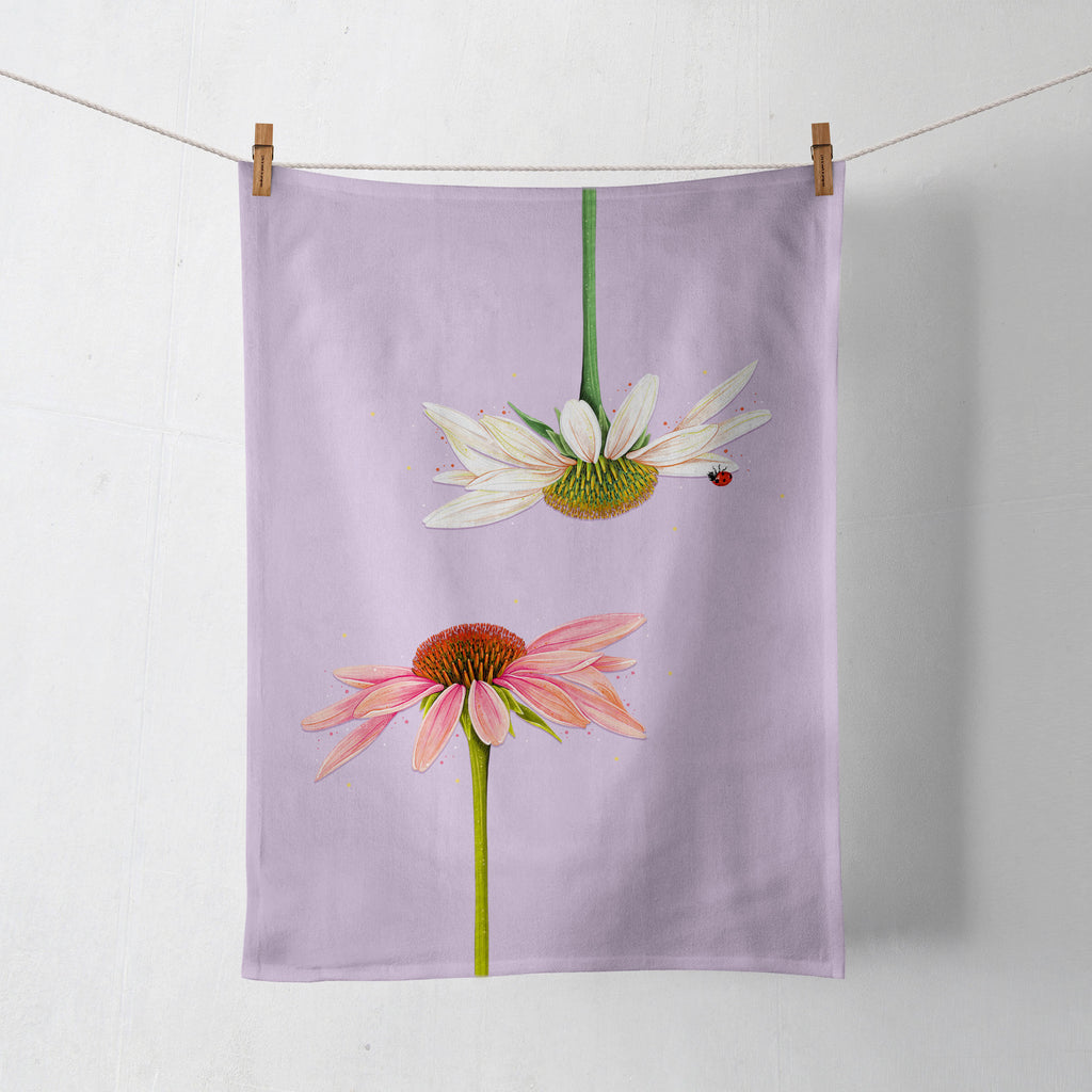 lilac tea towel with two echinacea daisies on it hanging on a washing line, held on with pegs